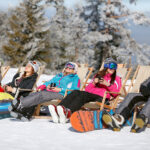 Skiiers and Snowborders taking a break in chairs on a sunny winter's day