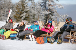 Skiiers and Snowborders taking a break in chairs on a sunny winter's day